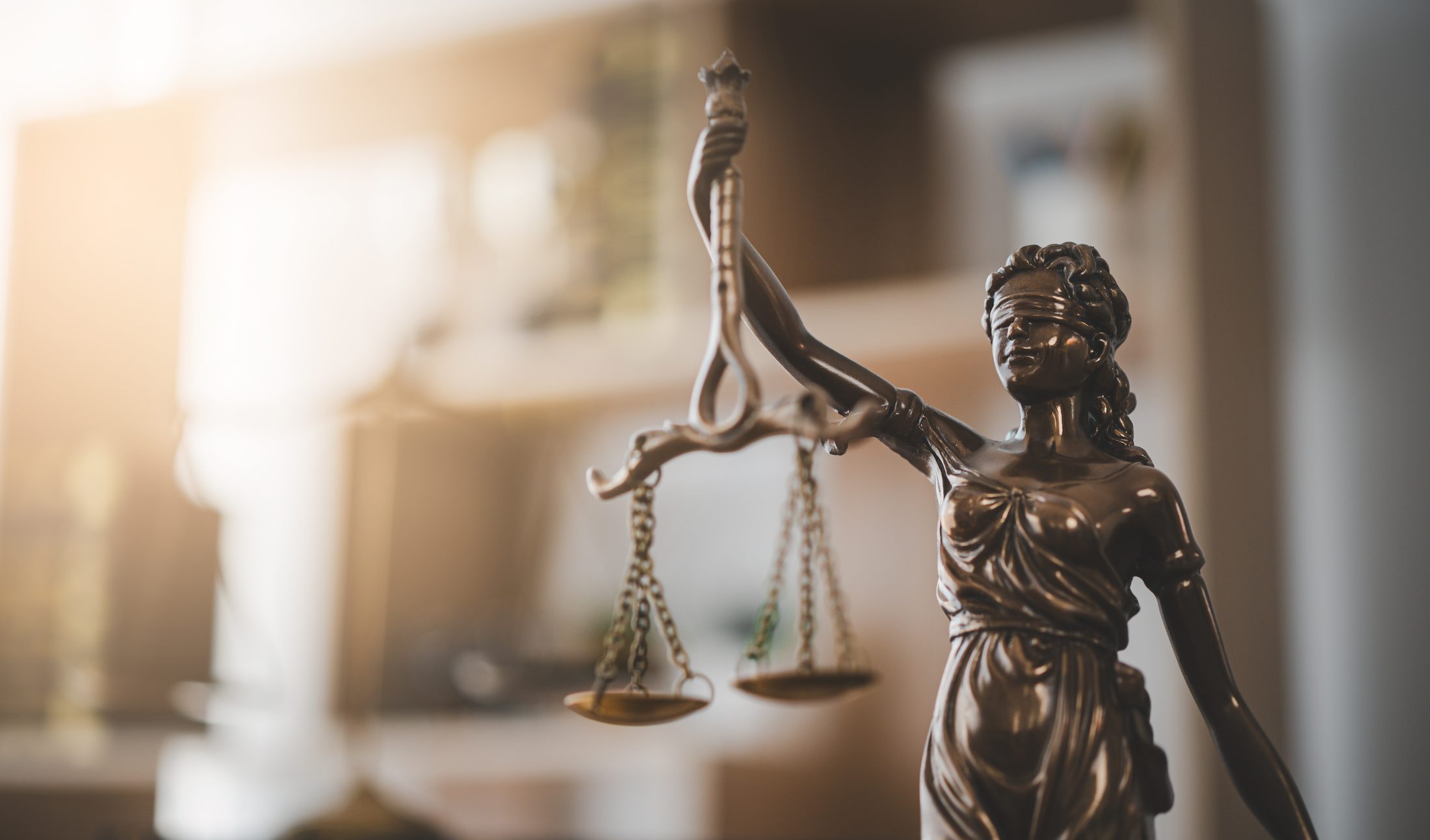 Illustrative bronze statue of Lady Justice in a sunlit office