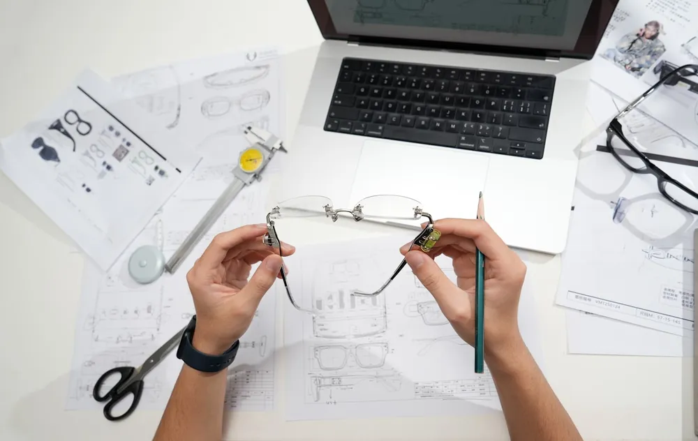 Illustrative photograph of hands examining a product design over technical drawings, representing intellectual property law.